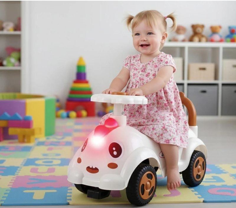 A smiling girl in a pink floral dress riding a white Funfizz ride-on car across a playroom mat