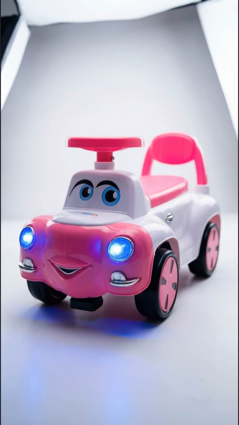 A pink Funfizz ride-on car with glowing blue headlights, photographed against a white studio backdrop